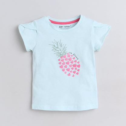 Light blue t-shirt with pink heart design on a beige background