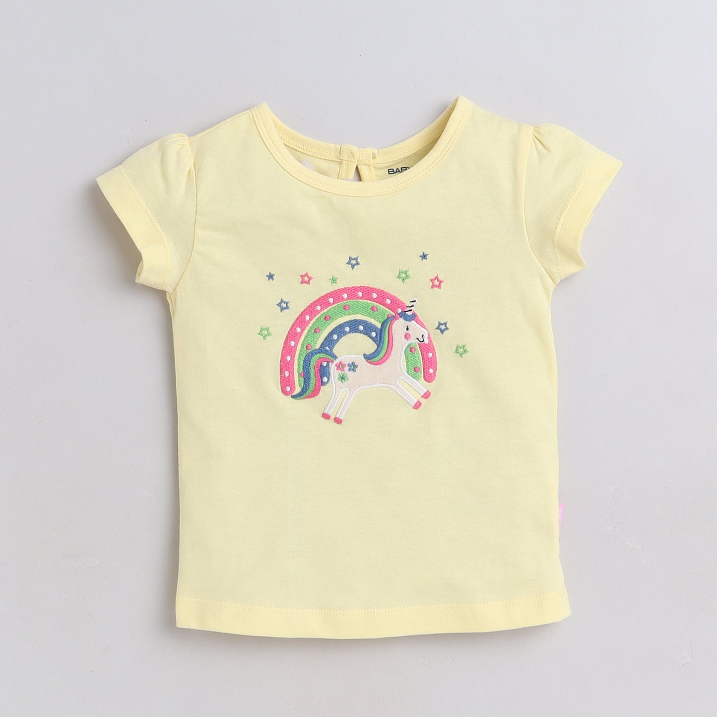 Yellow t-shirt with a colorful unicorn design on a light gray background
